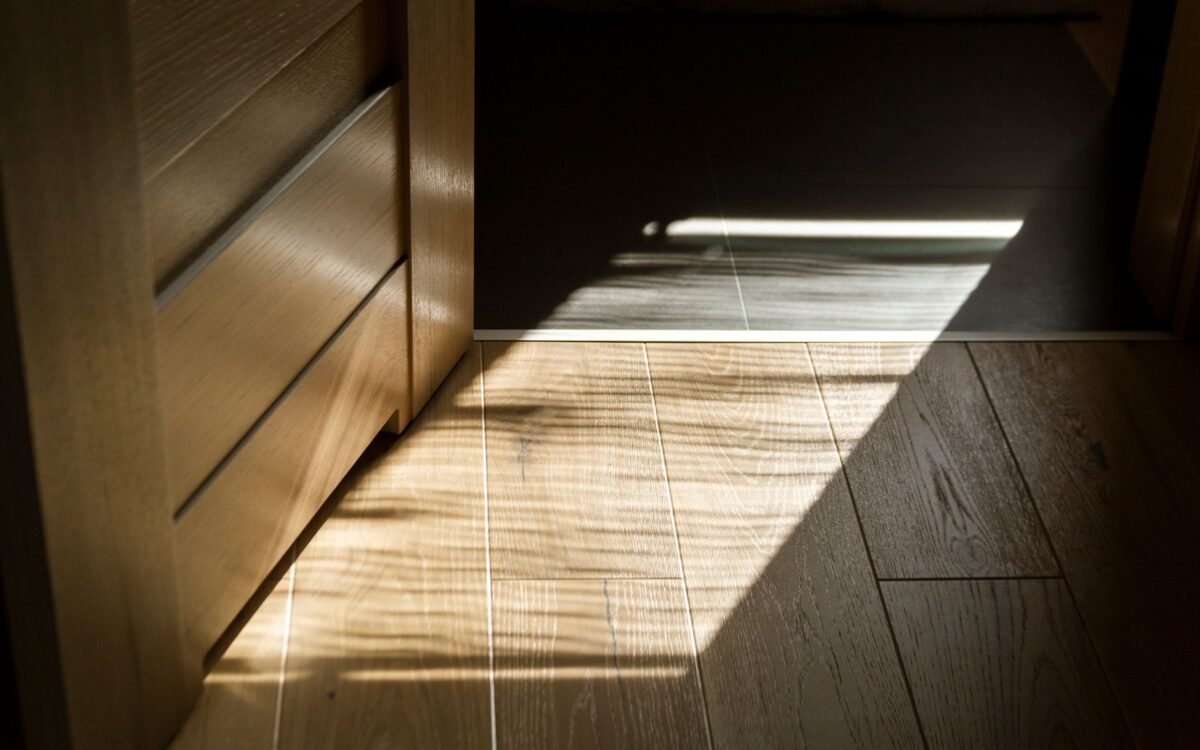 Sombras iluminadas pelo sol criam padrões no piso de parquete de madeira interior
