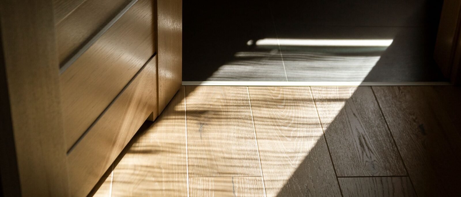 Sombras iluminadas pelo sol criam padrões no piso de parquete de madeira interior