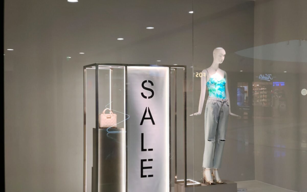 Vitrine elegante com placa de promoção e manequim fashionista em roupa moderna