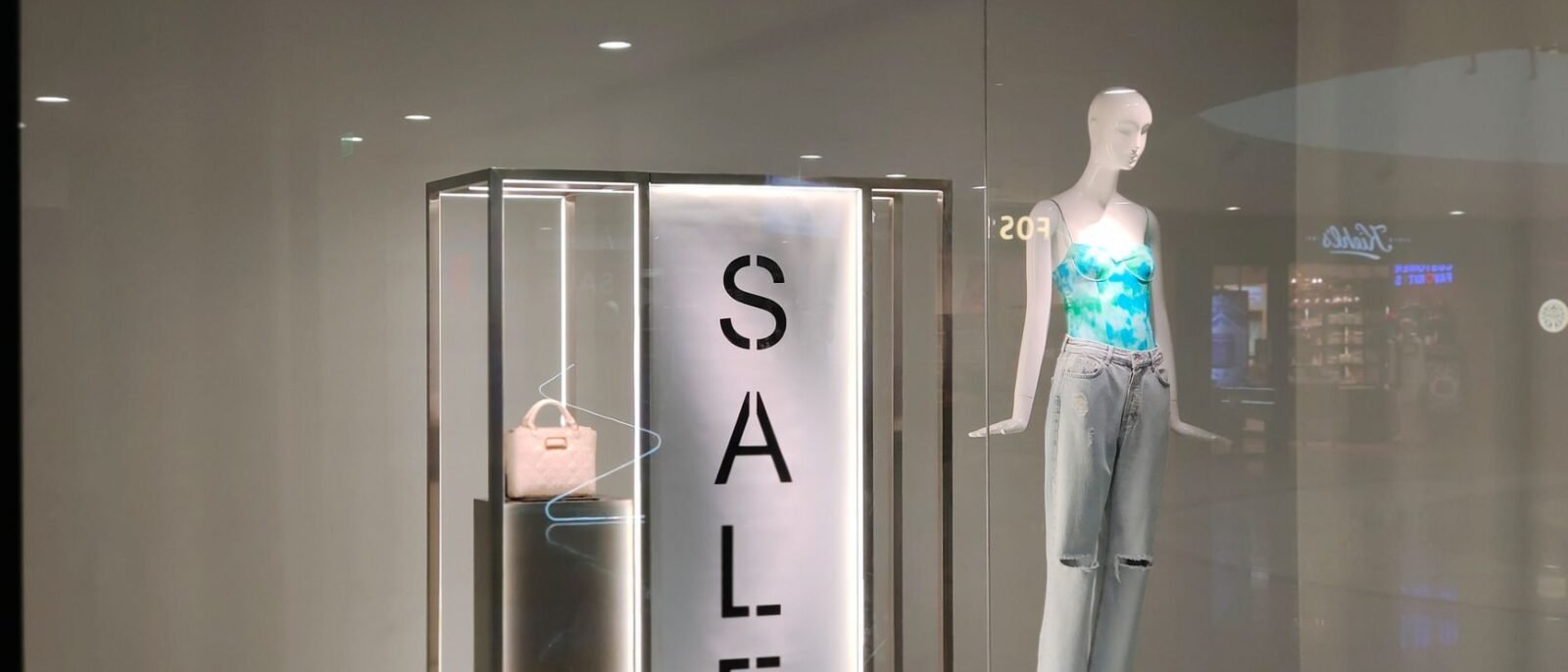 Vitrine elegante com placa de promoção e manequim fashionista em roupa moderna