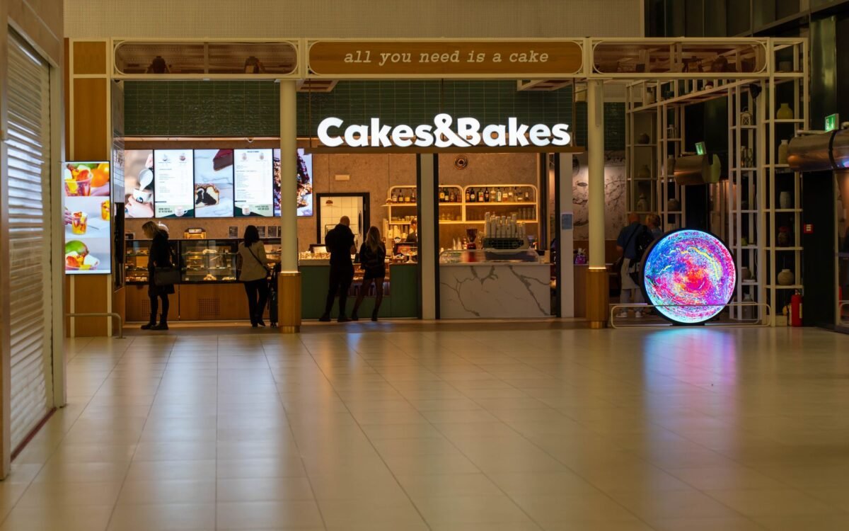 Uma padaria moderna, Cakes & Bakes, em um shopping de Zagreb à noite com compradores por perto