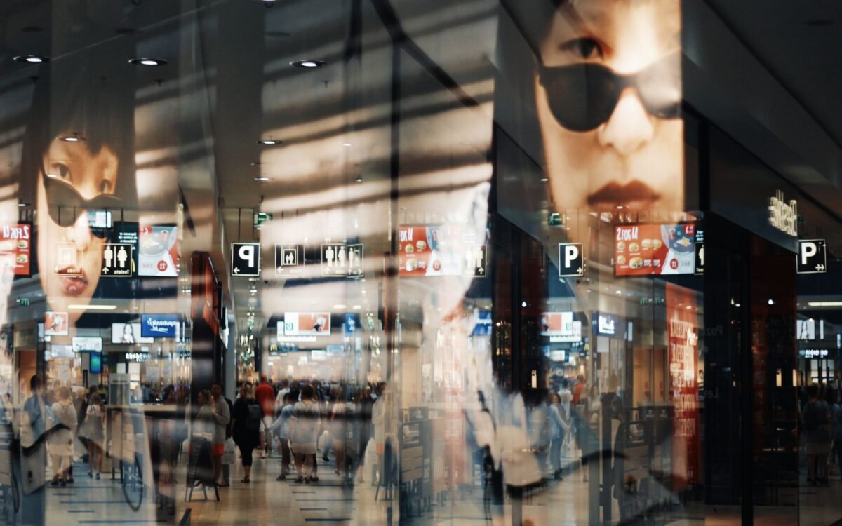 Reflexos de clientes e cartazes de moda em um shopping moderno com luzes brilhantes