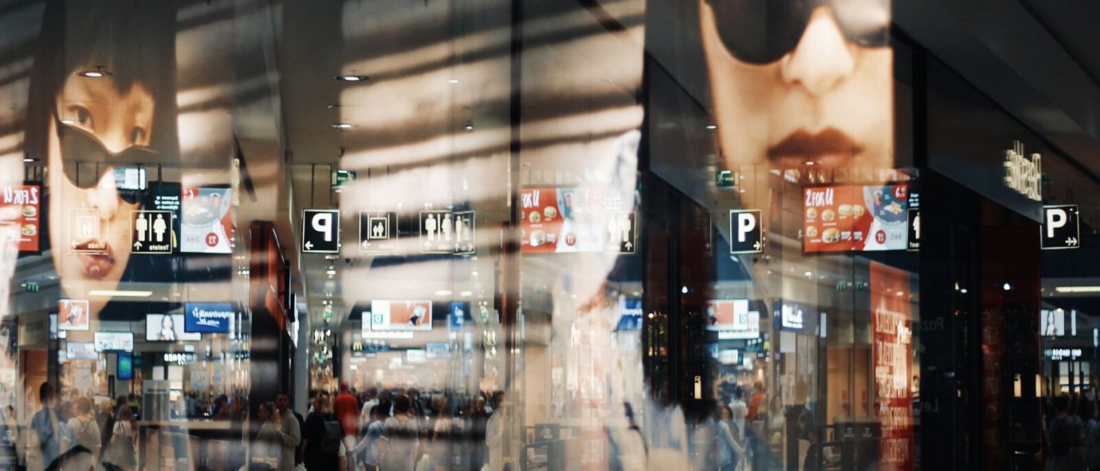 Reflexos de clientes e cartazes de moda em um shopping moderno com luzes brilhantes