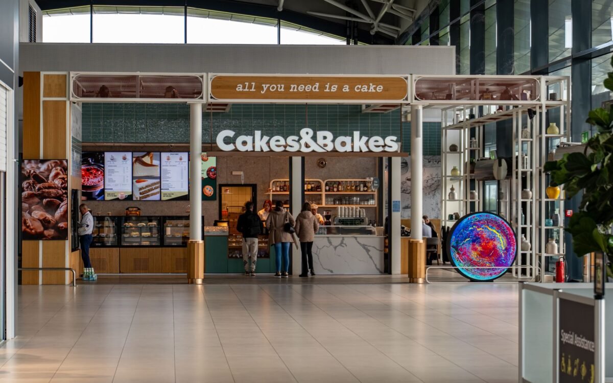 Vista interna da padaria Cakes & Bakes no Aeroporto de Zagreb com clientes e design contemporâneo