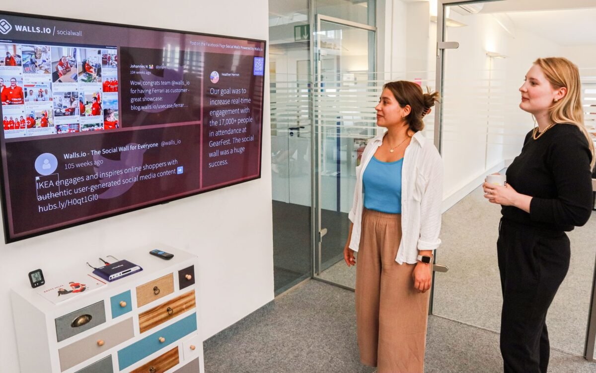 Duas mulheres interagem com uma apresentação digital em uma tela em um ambiente de escritório moderno