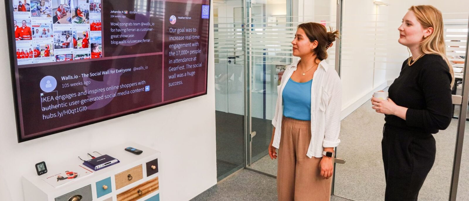 Duas mulheres interagem com uma apresentação digital em uma tela em um ambiente de escritório moderno