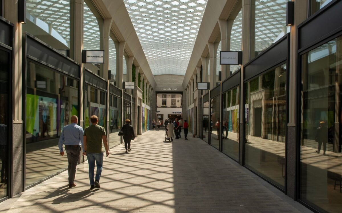Corredor interno movimentado com pessoas caminhando sob um teto de vidro moderno em Tilburg, Holanda