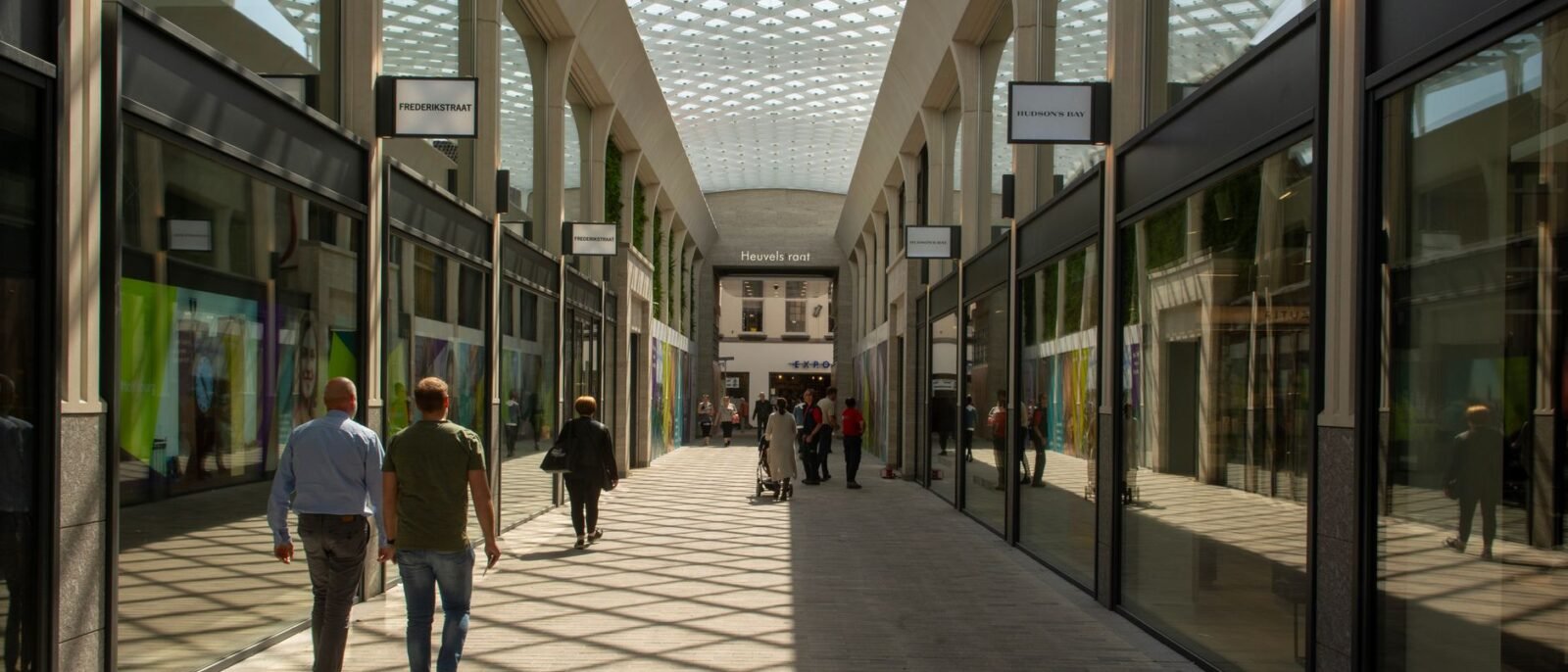 Corredor interno movimentado com pessoas caminhando sob um teto de vidro moderno em Tilburg, Holanda