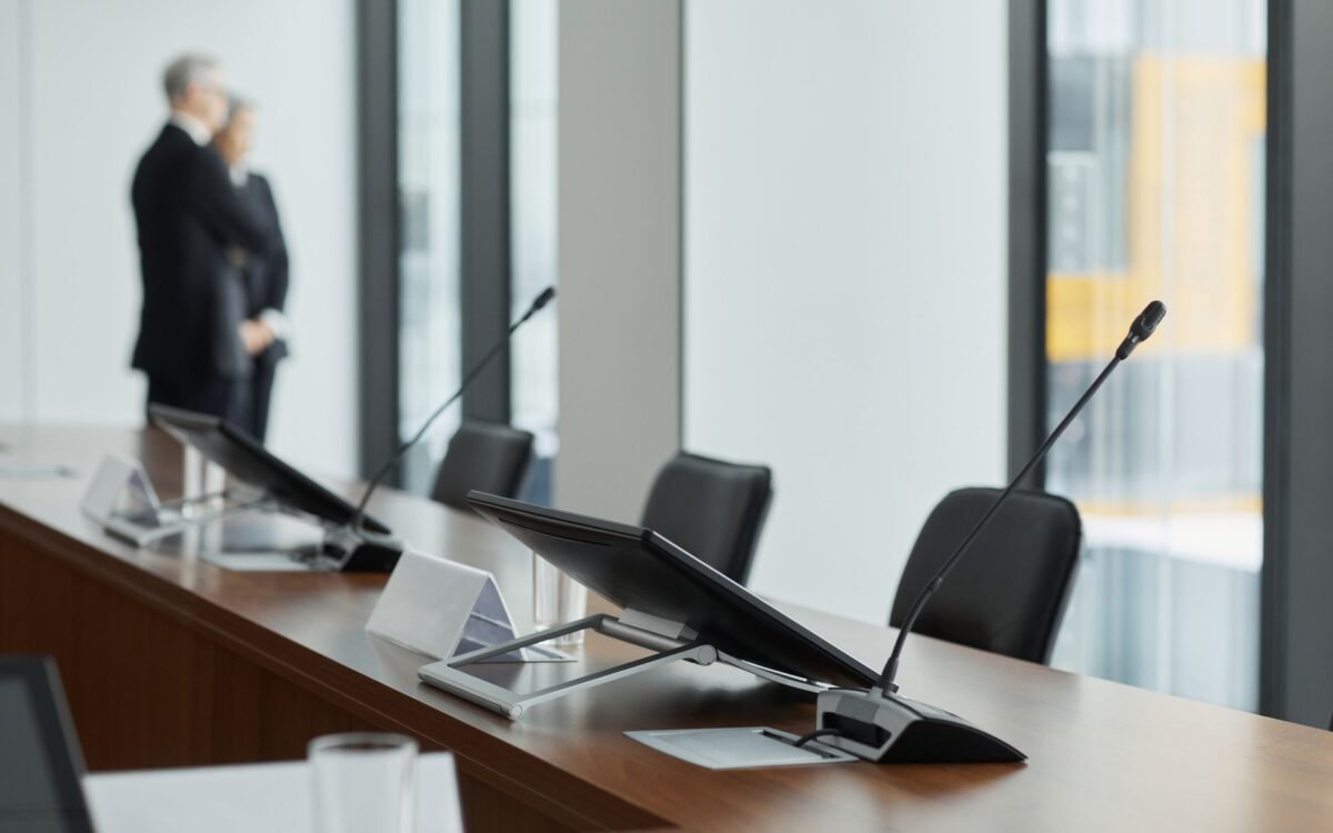 Elegante sala de conferência com microfones, displays digitais e elementos de design moderno
