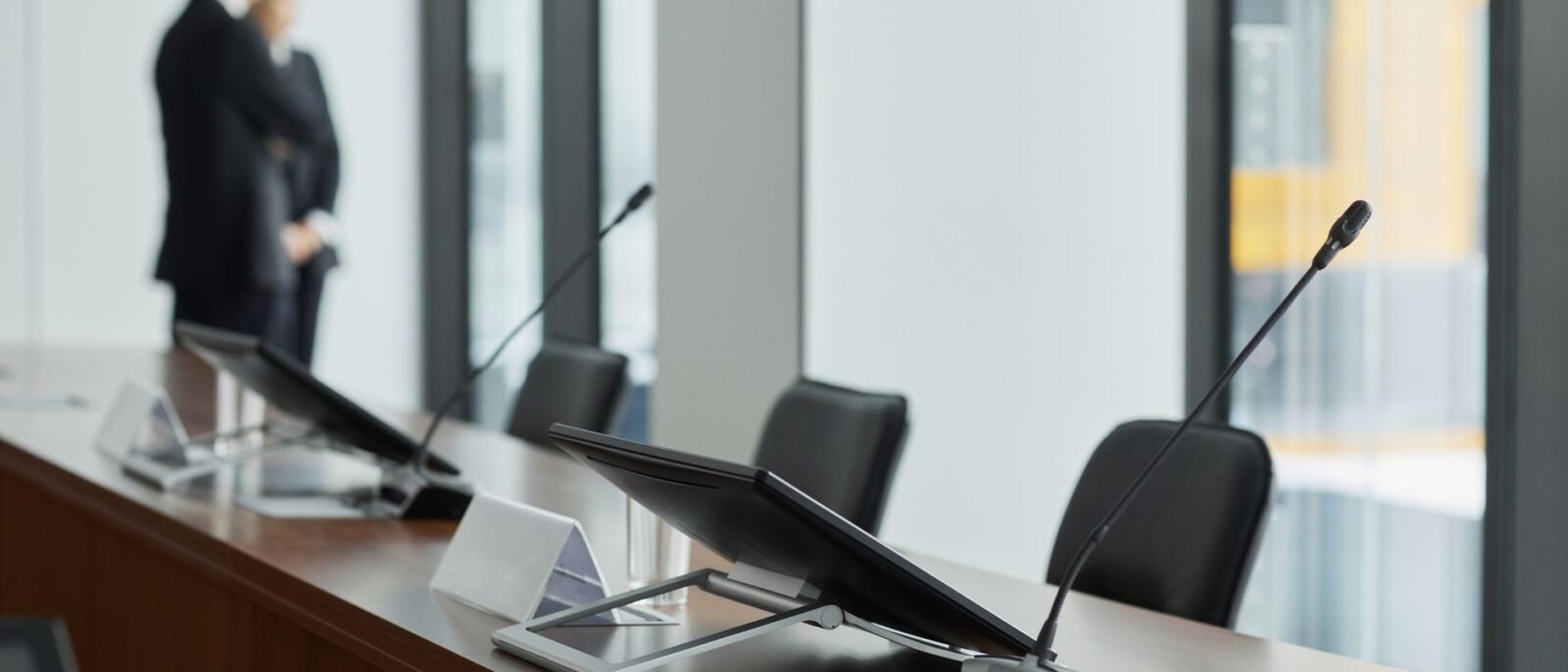 Elegante sala de conferência com microfones, displays digitais e elementos de design moderno